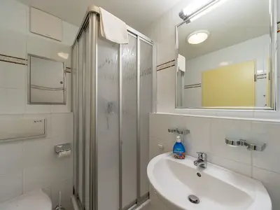 Badezimmer mit Dusche, WC, Waschtisch und Spiegel