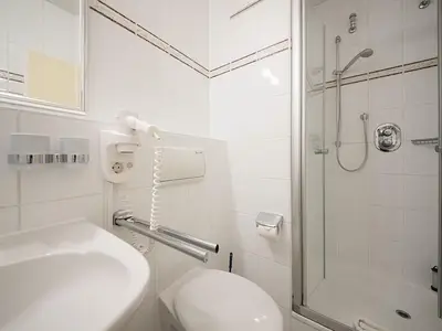 Badezimmer mit Dusche, WC, Waschtisch und Spiegel