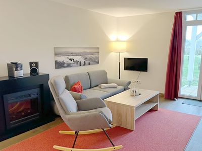 Wohnbereich mit Couch, Schaukelstuhl, Elektrokamin, Flatscreen TV und Zugang zur Terrasse