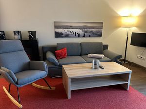 Wohnbereich mit Couch, Schaukelstuhl und Flatscreen TV