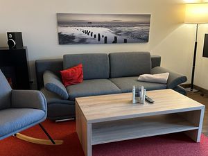 Wohnbereich mit Couch, Schaukelstuhl, Flatscreen TV und Zugang zur Terrasse