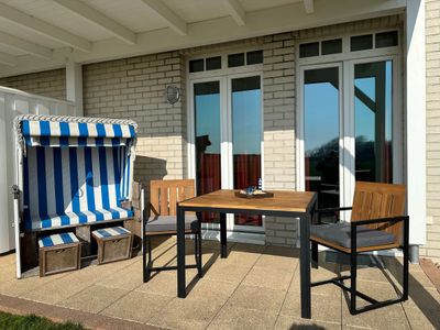 Überdachte Terrasse mit Strandkorb, Sitzgelegenheit und Grünfläche