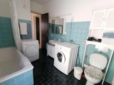 Badezimmer mit Badewanne, Waschmaschine und Trockner