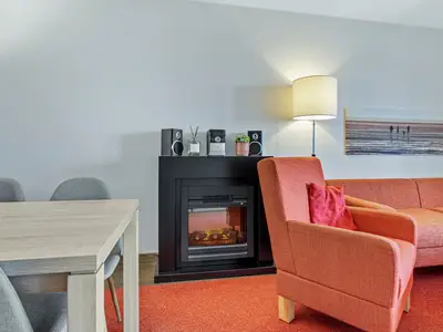 Wohnbereich mit Sofa, Sessel, Couchtisch und Kamin
