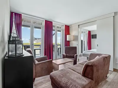 Wohnbereich mit Sofa, Sessel, Couchtisch mit Zugang zum Balkon