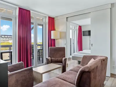 Wohnbereich mit Sofa, Sessel, Couchtisch mit Zugang zum Balkon