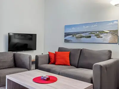 Wohnbereich mit Sofa, Sessel, Couchtisch und TV