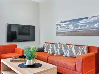 Wohnzimmer mit Couch, Couchtisch, Sessel und TV