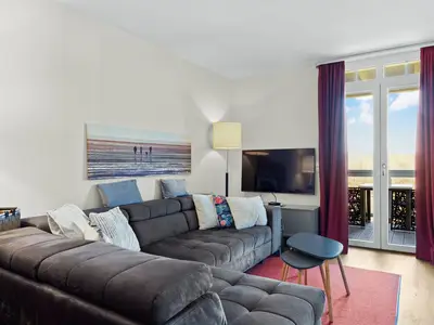 Wohnbereich mit Sofa, Couchtisch, TV und Zugang zum Balkon