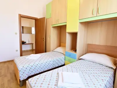 Schlafzimmer 2 mit zwei Einzelbetten und Kleiderschrank.