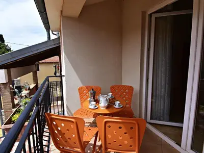 Die überdachte Terrasse ist mit Gartentisch und Stühlen ausgestattet.