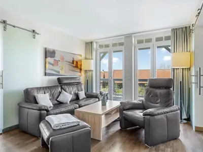 Wohnbereich mit Sofa, Sessel, Couchtisch und Zugang zum Balkon