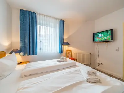 Schlafzimmer mit Doppelbett und TV