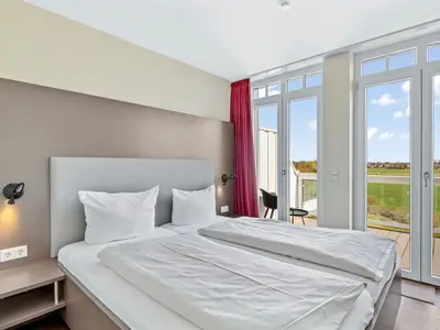 Schlafzimmer mit Doppelbett und Zugang zum Balkon