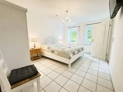 Großes Schlafzimmer mit Doppelbett, Fenstern, TV und Kleiderschrank
