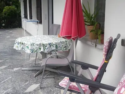 Aussensitzplatz mit Blick auf die Wohnung (die beiden Fenster mit Fensterläden)