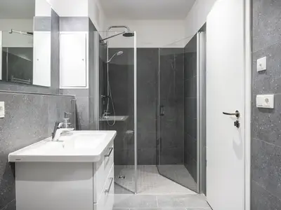 Badezimmer mit Dusche, Waschtisch, WC und Spiegel