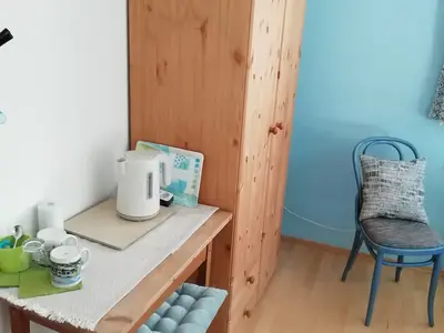 Blaues Zimmer mit Tisch und Stühle. In jedem Schrank sind Kleiderbügel sowie zwei Wolldecken