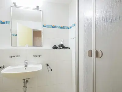 Badezimmer mit Dusche, Waschtisch, WC und Spiegel