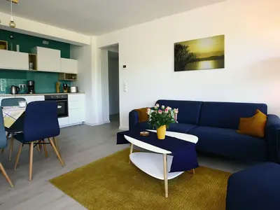 Wohn/Essbereich: Sofa, Sessel, TV, Zugang zum Balkon