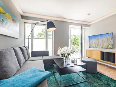 Wohnzimmer: Schlafsofa, Sitzhocker, TV, Zugang zum Balkon