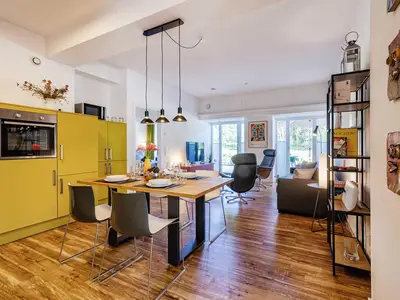 Offener Wohnbereich mit Zugang zur Terrasse, integrierter Küche, Esstisch, ausziehbarer Couch, Relaxsesseln, Smart-TV