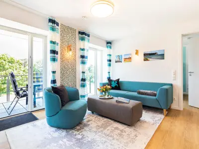 Wohn-/Essbereich: Sitzgruppe mit Couch und Sessel, Smart-TV, Zugang zum Balkon, Esstisch mit 5 Stühlen