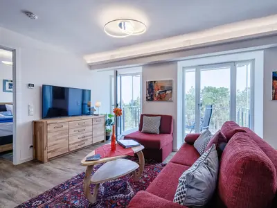 Wohnzimmer: Schlafsofa und Sessel, TV, Essbereich, Zugang zum Balkon