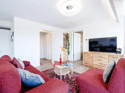 Wohnzimmer: Schlafsofa und Sessel, TV, Essbereich, Zugang zum Balkon
