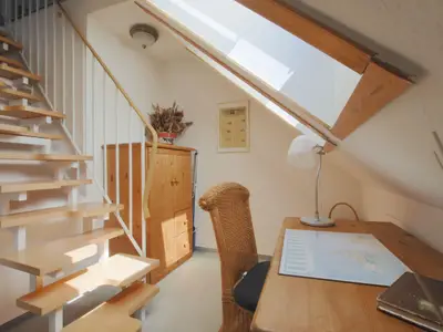 Kleines Zimmer mit Schreibtisch und Raumspartreppe in das Spitzd