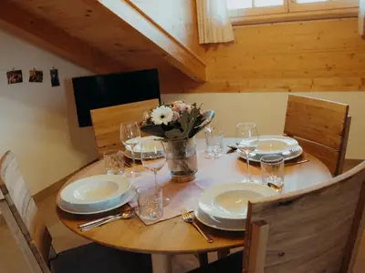 Wohnküche mit Esstisch und Fernseher im Hintergrund