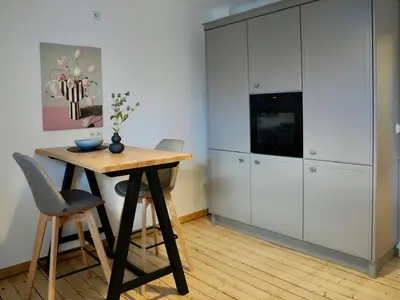 Die Küche mit Backofen, Kühlschrank und Esstisch