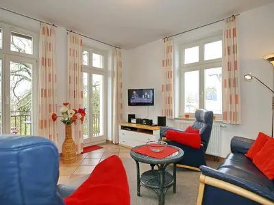 Wohnzimmer mit Sofa, Sesseln und TV