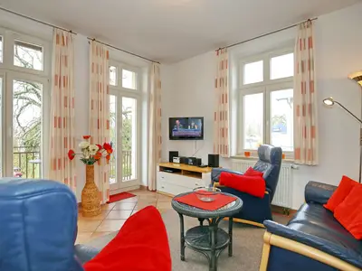 Wohnzimmer mit Sofa, Sesseln und TV