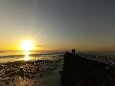 Sonnenuntergang am Strand mit Gehweg und Menschen