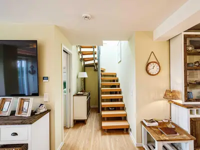 Wohnbereich/Essbereich: Sofa, TV, Treppenaufgang zur Dachterrasse, Zugang zum Balkon