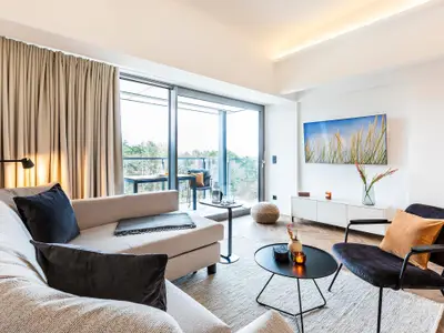 Wohn/Essbereich: Schlafsofa, Smart-TV, Zugang zum Balkon mit Strandkorb, Tisch und Stühlen