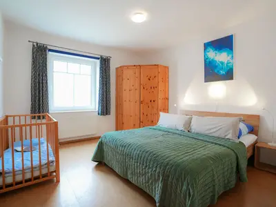 Geräumiges Schlafzimmer für entspannte Nächte mit Babybett.