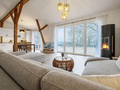 Offenes Wohnzimmer mit Couch, Meerblick, Ofen und Essbereich