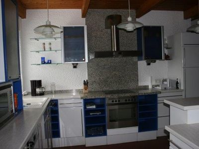 Küche mit Herd, Kochplatte, Mikrowelle, Kühlschrank und großer Arbeitsfläches