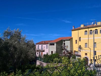 Außenansicht des Gebäudes. Im OG liegt die Fewo. da drüber die die Dachterrasse. mit Blick zum Meer und Berge.