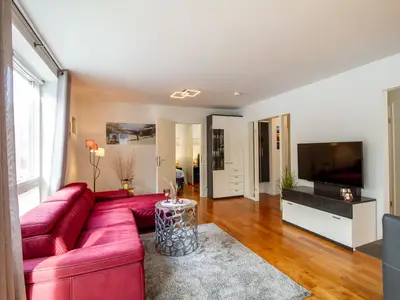 Ocean Club Timmendorfer Strand: Helles Wohnzimmer mit rotem Sofa und TV-Bereich.