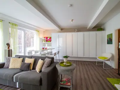 Helles Wohnzimmer mit Schlafcouch & Blick ins Grüne – Ferienwohnung Beach Lounge Timmendorfer Strand.