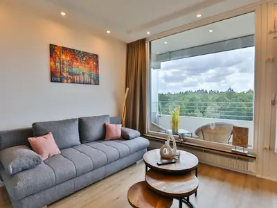 Strandkoje 6: Helle Sitzecke mit Sofa und Blick ins Grüne – Entspannen im modernen Apartment in Timmendorfer Strand.