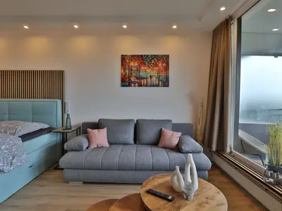 Strandkoje 6: Gemütliches Sofa und Boxspringbett am Panoramafenster – modernes Apartment in Timmendorfer Strand.