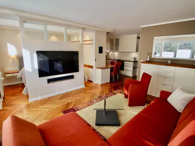 Gemütlicher Wohnbereich der Seepferdchen Suite mit großem Sofa, Sessel & 65-Zoll-Smart-TV – ideal für entspannte Abende.