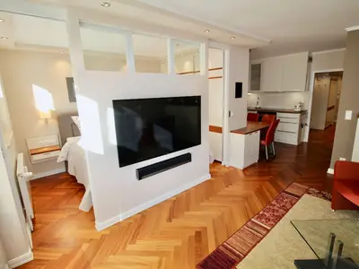 Seepferdchen Suite: Moderner Wohnbereich mit großem TV und Blick ins Schlafzimmer.
