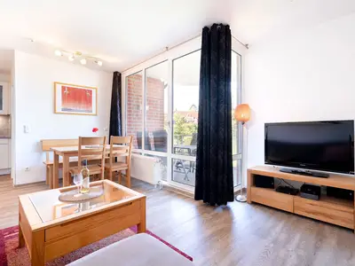 Wohnzimmer mit Couch, Fernseher und Sitzecke