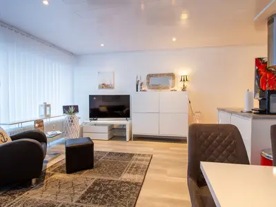Beach House 21 – Großzügiger Wohnraum mit TV, Küche und gemütlicher Sitzecke im Tageslicht.