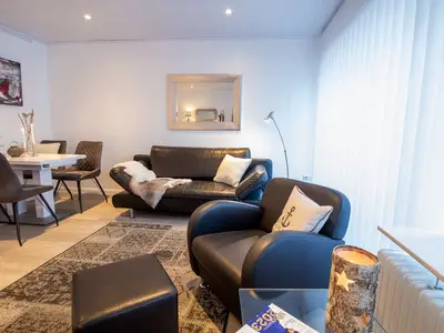 Beach House 21 – Heller Wohnbereich in der Ferienwohnung Timmendorfer Strand mit bequemer Ledercouch, Essplatz und stilv